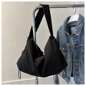 Detail of minimalist black hobo bag with drawstring accents and silver metal zipper