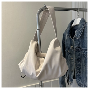 Detail of off-white ruched tote bag showing soft vegan leather texture and shoulder strap
