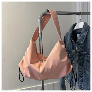 Detail of pink nylon crossbody bag with wide shoulder strap and drawstring accents