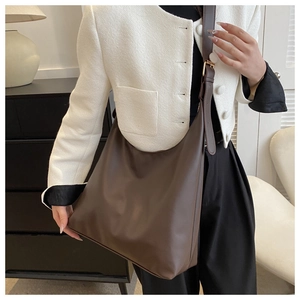 Detail of dark brown leather tote bag with adjustable shoulder strap and gold hardware