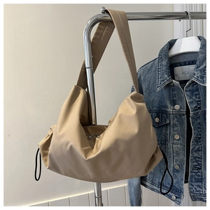 Close-up of khaki nylon gym bag on a hanger paired with a denim jacket for scale