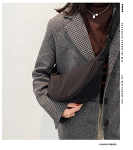 Side view of black nylon half-moon crossbody bag styled with a plaid blazer