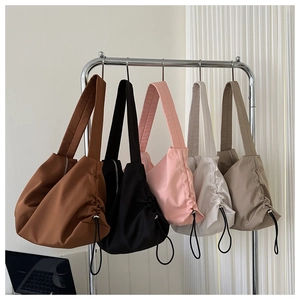 Detailed row of oversized pleated fitness bags in brown, black, pink, white, and khaki