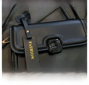 Detail view of black leather crossbody bag featuring a metallic FASHION charm