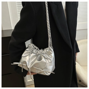 Detail of silver metallic bucket bag with leather bows and chain strap on black coat
