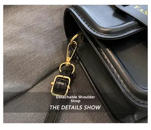 Detail showing the black leather handbag with a detachable strap and gold metal hardware