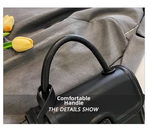 Close-up of the comfortable smooth leather handle on a chic black square handbag