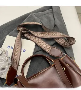 Dettaglio della borsa a secchiello in pelle marrone retrò con tracolla tessuta geometrica