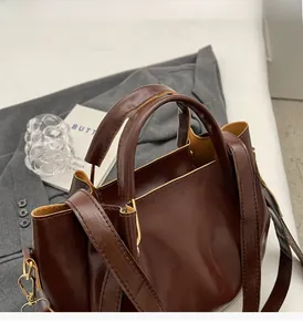 Dettaglio della borsa tote in pelle marrone scuro con finiture dorate e tracolla