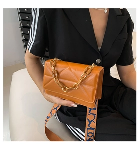 Detail of orange quilted crossbody bag with chain accent and bold blue print wide strap