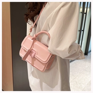 Detail of light pink glossy small square bag with circular handle and detachable strap