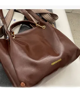 Dettaglio della borsa tote marrone scuro con trama liscia e tracolla intrecciata
