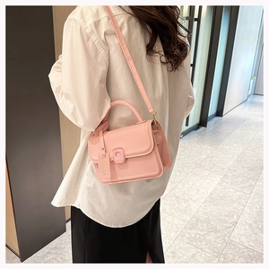 Pink glossy jelly bag with top handle and Fashion tag worn by model in hallway