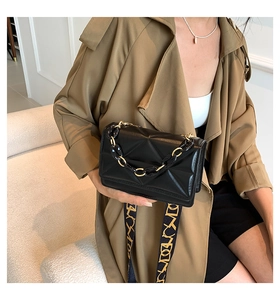 Detail of black geometric quilted crossbody bag with patterned wide strap and chain strap