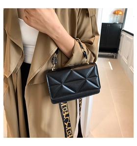 Detail of black geometric quilted handbag with wide logo strap and chain handle