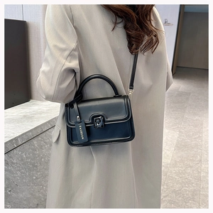 Detail of a chic black leather crossbody square bag with metallic lock and fashion tag