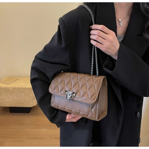 Brown quilted shoulder bag with silver chain strap worn over a black blazer