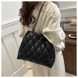 Quilted tote bag with chain strap shown on model to display size and fit for daily use