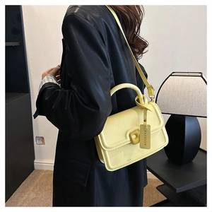 Detail of cream yellow leather handbag with doughnut-shaped buckle and leather tag