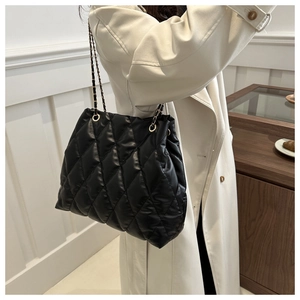 Detail of black quilted leather tote with elegant metal chain strap and golden eyelets