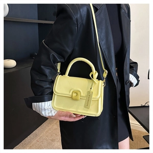 Detail of light yellow retro square bag featuring matte leather and a fashion brand tag