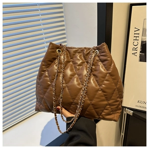 Detail of a brown quilted puffer tote bag with golden metal chain shoulder strap