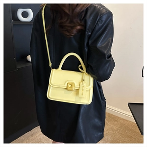 Detail of model wearing a bright yellow crossbody bag over a black leather jacket