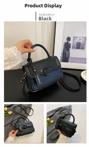 Detail of black crossbody bag featuring top handle and gold printed fashion hangtag