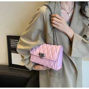 Pink quilted shoulder bag with dark silver chain strap and metal lock on trench coat