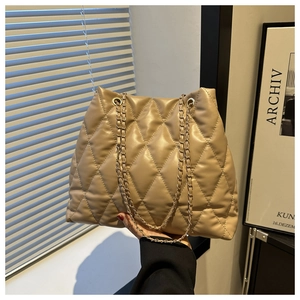 Detailed view of quilted faux leather texture and gold chain strap on a khaki tote bag
