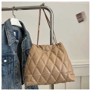 Close-up of beige quilted tote bag featuring gold chain straps and textured faux leather