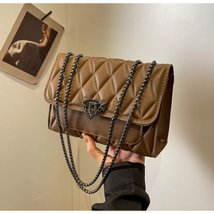 Detail of brown quilted shoulder bag featuring retro metal triangle lock and chain strap