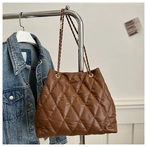 Detail of dark brown quilted tote bag with golden chain strap and rhombus stitching