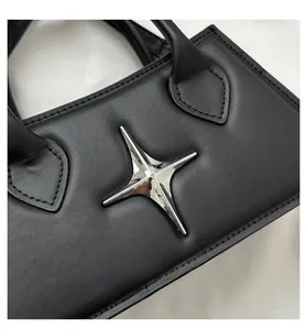 Close-up of black leather bag featuring a silver star ornament and neat stitching