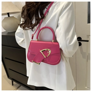 Detail of rose pink square bag with unique gold hardware and leather strap on a model