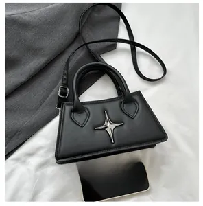 Macro view of black crossbody bag with silver star buckle and smartphone for size