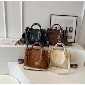 Dettaglio di quattro borse tote in pelle in vari colori con tracolle in tessuto fantasia