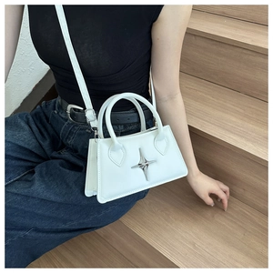 Detail of white vintage crossbody bag with silver star decor on model's hand