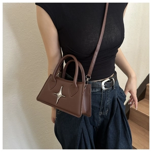 Brown trapezoidal crossbody bag with silver star metal accent shown on a model