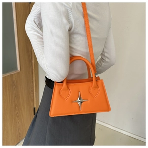 Detail of bright orange crossbody bag with silver star buckle and smooth leather texture