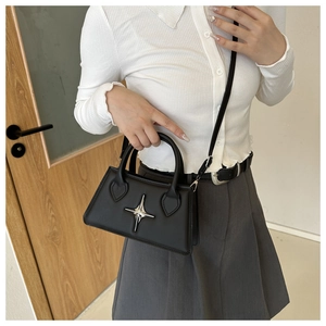 Detail of black leather crossbody bag with silver star hardware and handle