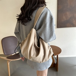 Minimalist beige drawstring pleated shoulder bag shown from back view on model