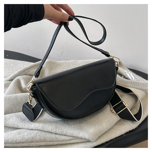 Detail showing the black saddle bag's unique wavy flap and two stylish shoulder straps
