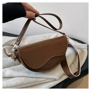 Detail of brown vintage saddle bag with embossed logo and wide woven shoulder strap
