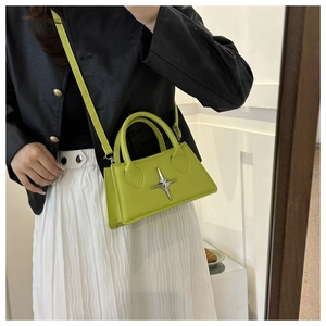 Detail of neon green square handbag with silver star accessory on leather surface