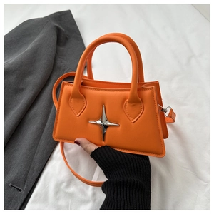 Detail of orange trapezoid crossbody bag featuring a silver star metal accessory