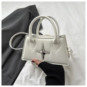 Detail of white trapezoid leather handbag with silver star metallic charm and top handle
