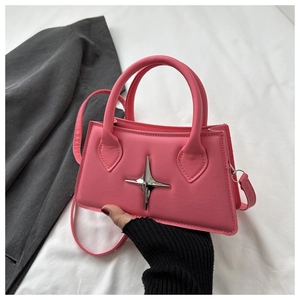 Detailed close-up of pink leather handbag with silver star ornament and tubular handle