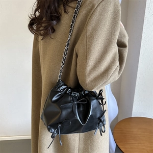 Fashionable black drawstring bucket bag with leather bows and silver chain strap for women
