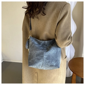 Détail du sac hobo en daim bleu marine avec bandoulière brodée et petit porte-monnaie